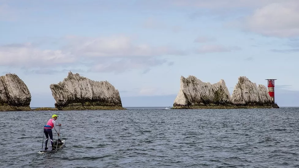 A woman paddleboarding near The Needles, Isle of Wight