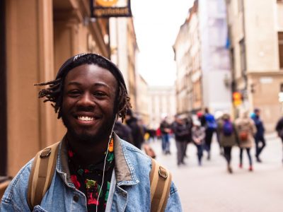 A young man smiling whilst walking through a city